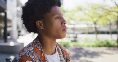 Şehirde Afro-Amerikalı bir adam, parkta oturmuş kahvesini içiyor. Dijital göçebe şehirde geziyor, dolaşıyor..