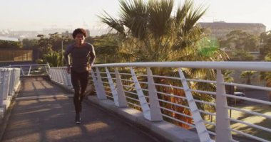 Sağlıklı Afro-Amerikan bir adam şehir dışında egzersiz yapıyor kulaklık takıyor, yaya köprüsünde koşuyor. fitness ve aktif şehir dışı yaşam tarzı.
