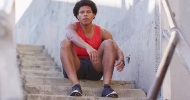 Afrika kökenli Amerikalı adam şehirde egzersiz yapıyor, merdivenlerde oturuyor ve ayakkabı bağcıklarını bağlıyor. fitness ve aktif şehir dışı yaşam tarzı.
