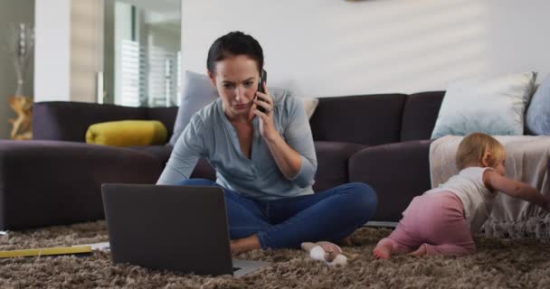 Mãe Branca Usando Laptop Falando Smartphone Enquanto Bebê Rastejando Chão — Vídeo de Stock