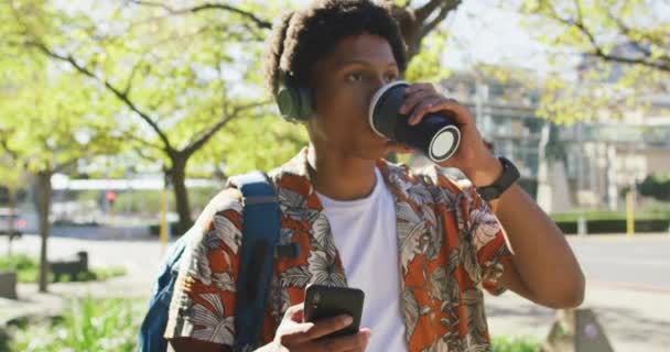 Glad Afrikansk Amerikansk Man Stan Med Smartphone Och Hörlurar Dricka — Stockvideo