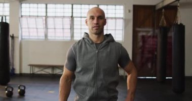 Spor salonunda gülümseyen kalçasında elleri olan beyaz bir adamın portresi. Spor, antrenman ve spor konsepti