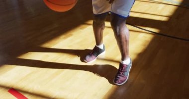 Afrikalı Amerikalı erkek basketbolcu top sürme pratiği yapıyor. Basketbol, kapalı sahada spor eğitimi..