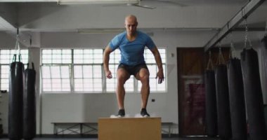 Spor salonunda beyaz bir adam pilo kutusunun üstüne atlıyor. Spor, antrenman ve spor konsepti