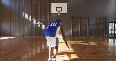 Afrikalı Amerikalı erkek basketbolcu topla atış pratiği yapıyor. Basketbol, kapalı sahada spor eğitimi..