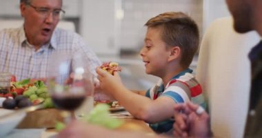 Mutlu beyaz büyükbaba aile yemeği sırasında torununu masada yemek yerken izliyor. çok nesildir birlikte evde vakit geçiriyoruz..