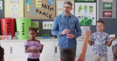 Sınıfta durup çöp toplamayı öğrenen çeşitli öğretmenler ve öğrenciler. İlkokuldaki çocuklar.