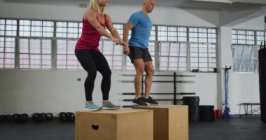 Beyaz kadın ve erkek spor salonundaki pilo kutularına atlıyor. Spor, antrenman ve spor konsepti