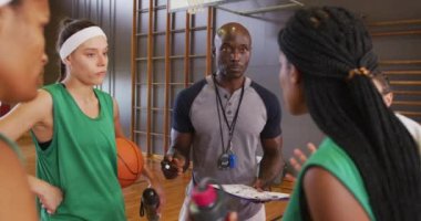 Çeşitli bayan basketbol takımı ve koç oyun taktiklerini tartışıyor. Basketbol, kapalı sahada spor eğitimi..