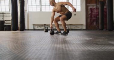 Kafkasyalı bir adam spor salonunda kettle Bell ile çalışıyor. Spor, antrenman ve spor konsepti
