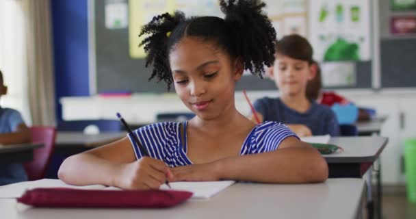 Portrett Lykkelig Skolepike Med Blandet Rase Som Sitter Klasserommet Noterer – stockvideo