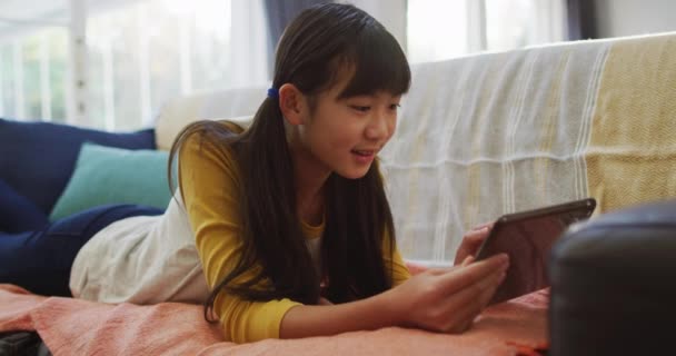 Asian Girl Smiling Using Tablet Lying Sofa Home Childhood Technology — Stock Video