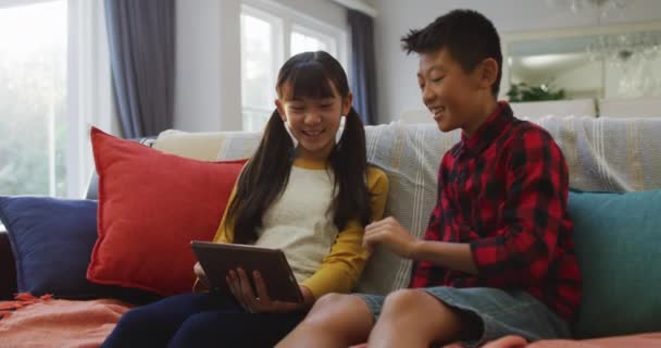 Aziatische Broer Zus Glimlachend Met Behulp Van Tablet Zitten Bank — Stockvideo