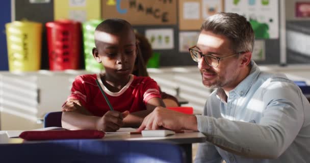 Diverse Happy Male Teacher Helping Schoolboy Sitting Classroom Learning Children — Stock Video