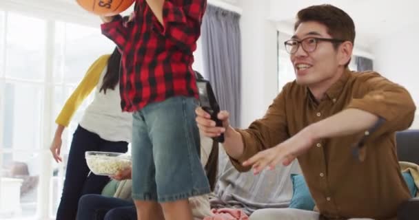 Emocionados Padres Asiáticos Con Hija Hijo Sofá Con Baloncesto Viendo — Vídeo de stock