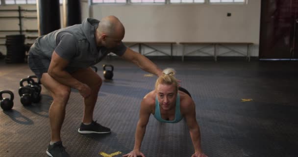 Erkek Antrenör Spor Salonunda Egzersiz Yaparken Beyaz Kadın Formunu Düzeltiyor — Stok video