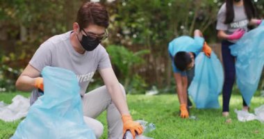 Asyalı ebeveynler, oğul ve kız yüz maskesi takıyorlar ellerinde çöp torbaları, plastik atık topluyorlar. Çevre koruma gönüllüleri Coronavirus covid19 salgını sırasında kırsal bölgeleri temizliyor.. .