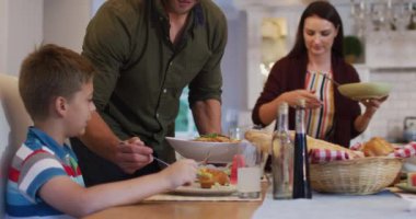 Gülümseyen beyaz baba aile yemeğinden önce masada durup oğluna yemek servisi yapıyor. çok nesildir birlikte evde vakit geçiriyoruz..