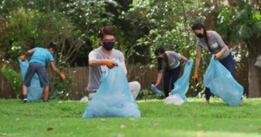 Asyalı ebeveynler, oğul ve kız yüz maskesi takıyorlar ellerinde çöp torbaları, plastik atık topluyorlar. Çevre koruma gönüllüleri Coronavirus covid19 salgını sırasında kırsal bölgeleri temizliyor.. .