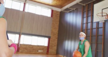 Farklı bayan basketbol takımları dirseklerle karşılanıyor, yüz maskeleri takıyorlar. Basketbol, kapalı bir sahada spor eğitimi Coronavirus covid 19 salgını sırasında.