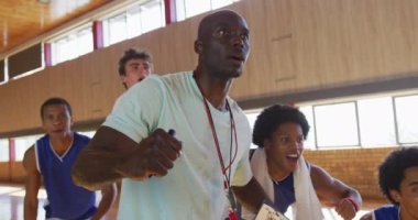 Çeşitli erkek basketbol takımı ve koç birlikte kutlama yapıyor. Basketbol, kapalı sahada spor eğitimi..