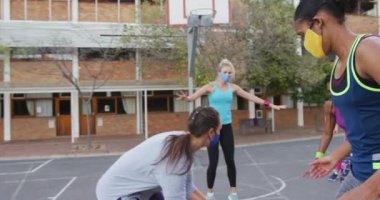 Yüz maskeleri takan çeşitli bayan basketbol takımları maç yapıyor ve gol atıyorlar. Coronavirus covid 19 salgını sırasında şehir merkezinde basketbol antrenmanı..