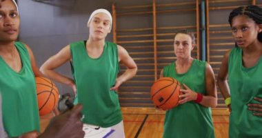 Çeşitli bayan basketbol takımı ve koç oyun taktiklerini tartışıyor. Basketbol, kapalı sahada spor eğitimi..