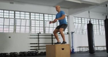 Spor salonunda beyaz bir adam pilo kutusunun üstüne atlıyor. Spor, antrenman ve spor konsepti