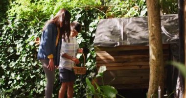 Mutlu Asyalı erkek ve kız kardeşler sepet taşıyor, bahçedeki kümesten yumurta topluyorlar. Karantina süresince evde tecrit altında..