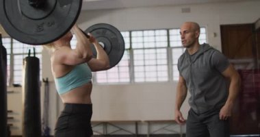 Beyaz kadın, spor salonunda erkek antrenörle halterle çalışıyor. Spor, antrenman ve spor konsepti