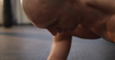 Beyaz kaslı, üstsüz kel adam egzersiz yapıyor ve tahta yapıyor. Spor salonunda sağlık ve spor eğitimi.