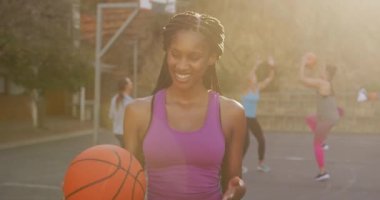Afrikalı Amerikalı bayan basketbolcunun portresi. Top tutuyor ve kameraya bakıyor. Basketbol, şehir merkezinde spor eğitimi..