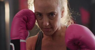 Boks eldivenli kadın boksör, spor salonunda yumruklarını çalışıyor. Spor, antrenman ve spor konsepti