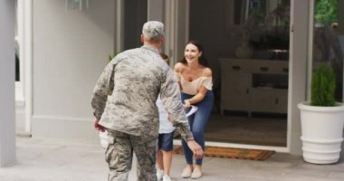 Mutlu beyaz erkek asker oğlunu ve karısını evlerinin önünde karşılıyor. Asker evine, ailesine dönüyor..
