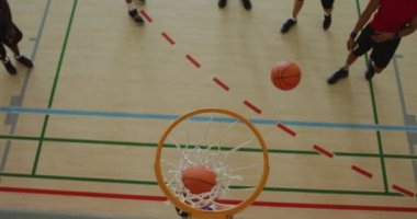 Afrika kökenli Amerikalı erkek basketbolcunun farklı oyunculara gol atması. Basketbol, kapalı sahada spor eğitimi..