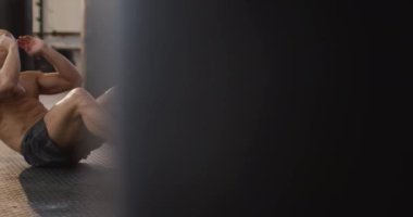 Beyaz, kaslı, üstsüz kel adam egzersiz yapıyor, mekik çekiyor. Spor salonunda sağlık ve spor eğitimi.