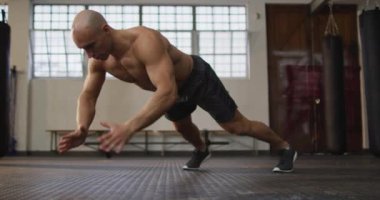 Beyaz, kaslı, üstsüz kel adam egzersiz yapıyor, şınav çekiyor. Spor salonunda sağlık ve spor eğitimi.