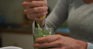 Beyaz kadın limon sıkıyor ve mutfakta yeşil sebze suyu hazırlıyor. ev hayatı, yemek ve sağlıklı yaşam konsepti.
