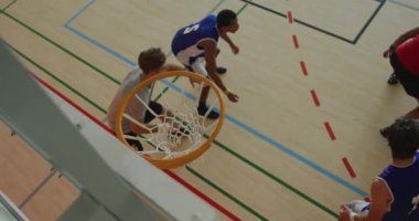 Afrika kökenli Amerikalı erkek basketbolcunun farklı oyunculara gol atması. Basketbol, kapalı sahada spor eğitimi..