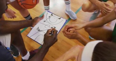 Çeşitli bayan basketbol takımı ve koç oyun taktiklerini tartışıyor. Basketbol, kapalı sahada spor eğitimi..