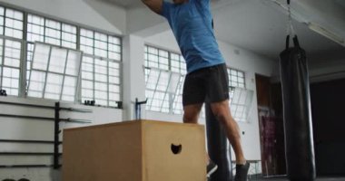 Spor salonunda beyaz bir adam pilo kutusunun üstüne atlıyor. Spor, antrenman ve spor konsepti