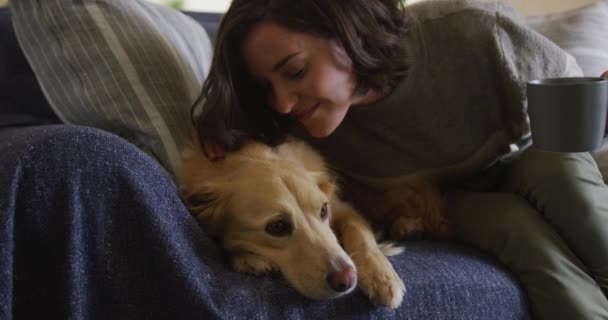 笑顔の白人女性がペットの犬と自宅でソファに座ってキスをします ライフスタイルペット友情動物の友情の概念 — ストック動画