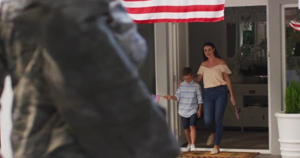 Кавказский Солдат Приветствует Сына Жену Саду Американским Флагом Висящим Снаружи — стоковое видео
