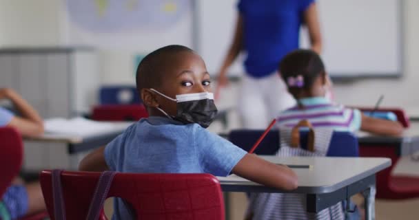 Retrato Colegial Afroamericano Sentado Aula Tomando Notas Con Máscara Facial — Vídeos de Stock