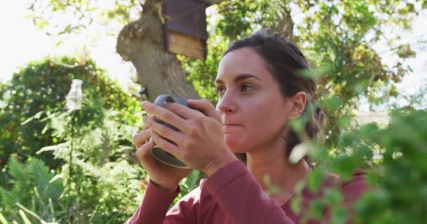 微笑的高加索女人坐在阳光灿烂的花园里喝茶 家庭生活和闲暇时间概念 — 图库视频影像