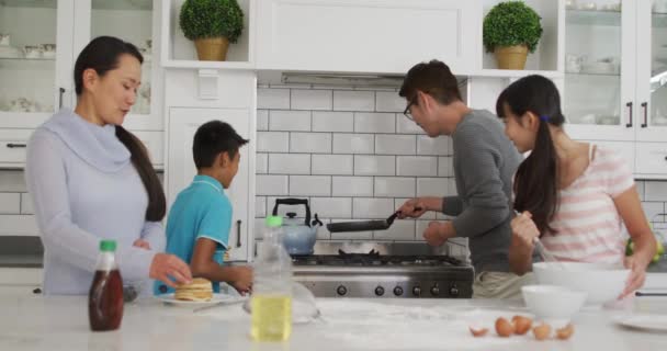 快乐的亚洲父母带着儿子和女儿在厨房里 父亲一边翻着煎饼一边看 快乐的家庭 在隔离隔离期间在家里 — 图库视频影像