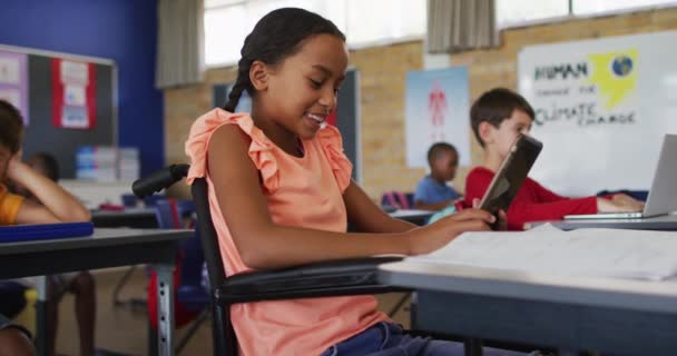 Vegyes Verseny Iskolás Lány Tolószékben Osztályteremben Tablettával Kollégák Háttérben Általános — Stock videók