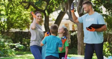 Gülümseyen beyaz aileler, açık havada plastik atıklar toplayıp beşlik çakıyorlar. Çevre koruma gönüllüleri kırsal alanda temizlik yapıyor.