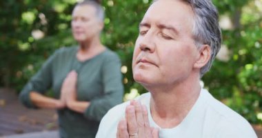 Birlikte yoga yapan ve bahçede otururken gülümseyen Kafkasyalı rahat bir çift. sağlıklı emeklilik yaşam tarzı.