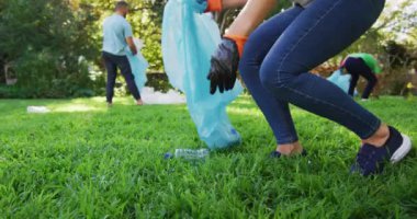 Elinde çöp torbası tutan gülümseyen beyaz anne koca ve oğluyla plastik atık topluyor. Çevre koruma gönüllüleri kırsal alanda temizlik yapıyor..